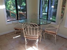 Wrought iron oval shaped glass top table and four chairs. Chairs have wood seats.
