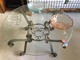 Coffee table with iron scroll work base under round glass top