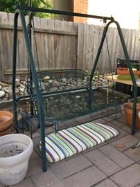 Green metal swing, outdoor glider with cushion on ground so you can see seat, exc.  condition