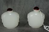 Two Chinese carved white jade snuff bottles with amber stoppers. H: 3 1/4"