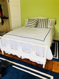 Vintage double bed, hand-painted in white. Two blue and white rugs. 