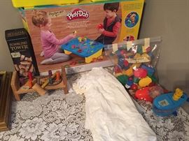 children's toys including a like new trike, a never used baby bed, and do you see the vintage fine baby clothes?