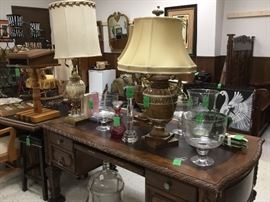 Under the desk us a great old bottle in a stand, on top we have decorator items and lamps