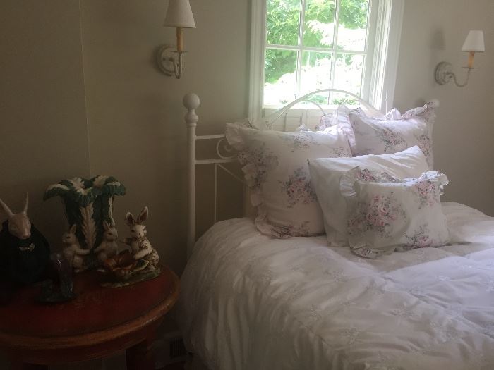Queen Iron bed, with duvet and shams, round side table shown with porcelain and wood "bunnies"