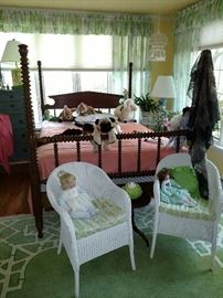 View of bed along with a pair of wicker chairs and dolls
