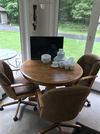 Dinette set with chairs on casters.  Flatscreen TV and set of white dishes.