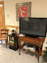 Nice Panasonic flat screen TV on table.  Golf themed stand and a caned seat chair