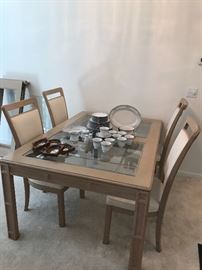 Light wood and beveled glass top dining table with chairs and a leaf
