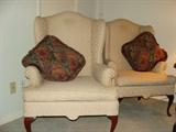 Beige Wing Back chairs with leaf pattern quilt. Wood pedestal legs.