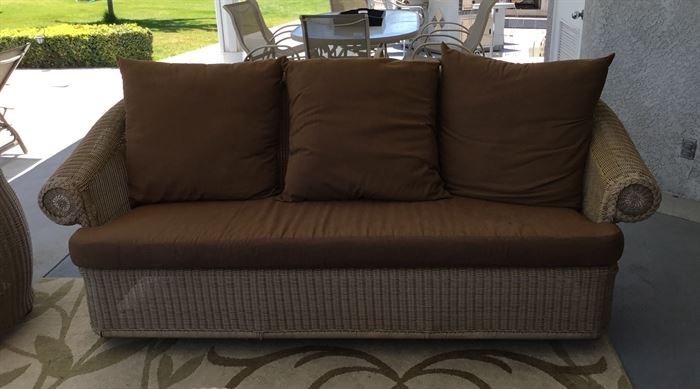 Wicker outdoor couch with brown cushions.