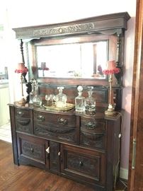 Gorgeous old server with mirrored top. Carved details and a beautiful dark wood. Decanter collection & cute candlestick lamps. 