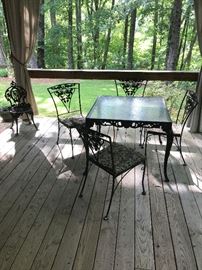 Wrought iron glass top patio table with 5 matching chairs.