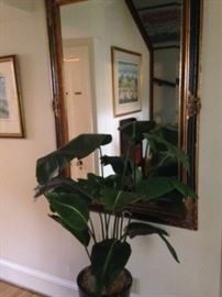 Rectangular gold and black mirror; large artificial plant