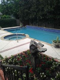 Hidden treasures in the backyard: a swimming pool, beautiful gardens, and a concrete bird sculpture.