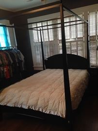 The master bedroom has a black queen canopy bed.