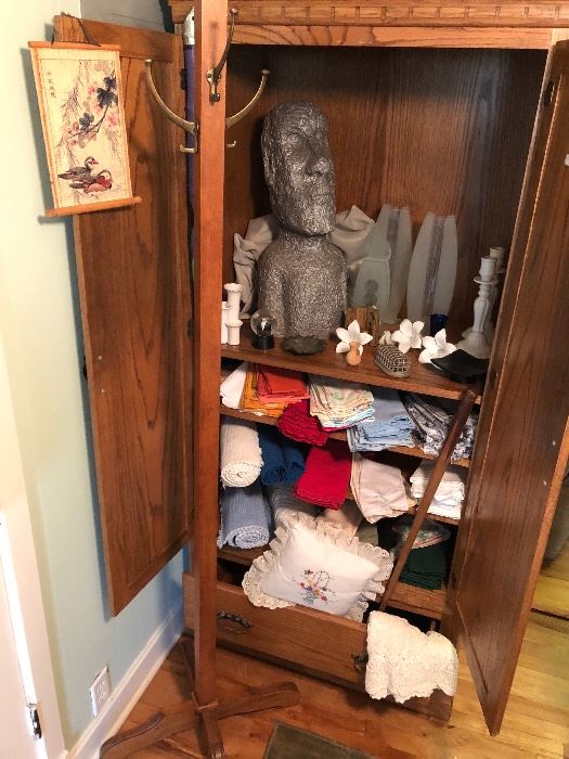 a cabinet full of the unusual- linens, glass and table top items. Check out our friend who looks like he is from Easter Island! Not to mention the coat rack