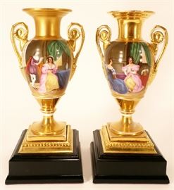 Pair of hand painted, gilt decorated porcelain urns on bases. with classical scenes