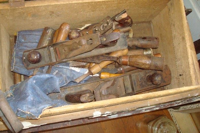 Old wood chest containing planes and wood chisels.