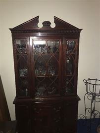 Mahogany China cabinet,  iron plant stand to the right. Top row contains vintage etched Crystal. Second row has heavy crystal tumblers. height 6'3".