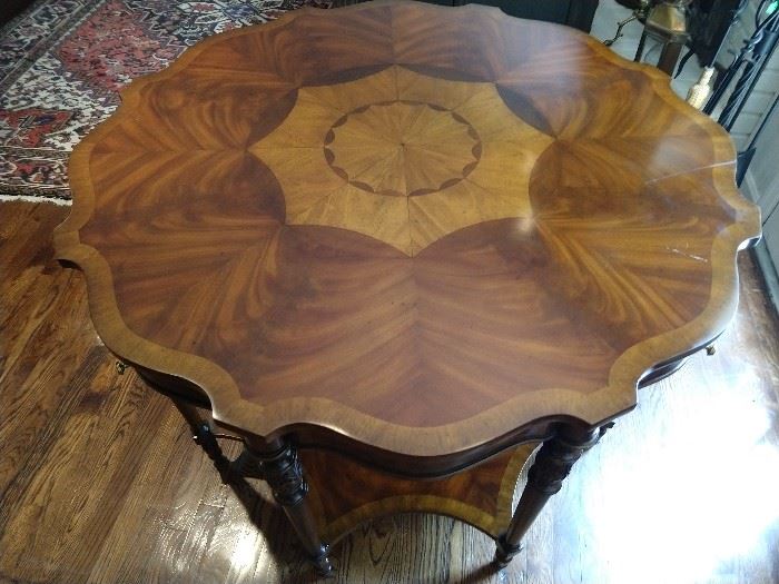 Wonderful Maitland-Smith octagonal mahogany and rosewood tiered foyer table. This large piece has cross banded mahogany to the octagonally scalloped top surrounding a scalloped radiating rosewood veneer inlay overhanging four small drawers with brass pulls and ormolu around the side. The table rises on eight turned legs connected by an eight-sided, rosewood stretcher shelf. Marked Maitland-Smith to the interior of the drawer. Purchased in 1992, for $4,500.00.