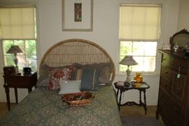 Full view of the Full bed with wicker head board. Bed has mattress and box springs.