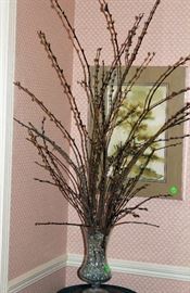 Pussy Willow stems in glass vase on round plant stand with marble top.