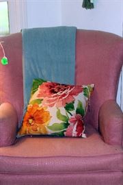 Rose colored chair with throw and pillow in living room.