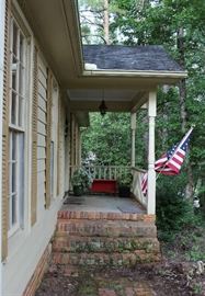 This is the front porch with red bench and flowers in pots.