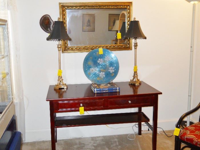 desk/table with 2 drawers, candlestick lamps w/shades, gold framed mirror, carved Indian head, etc.