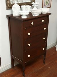 Small size chest of four drawers with porcelain knobs, displaying collection of milk glass.