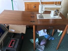 Old sears electric sewing machine attached to sewing table with various accessories