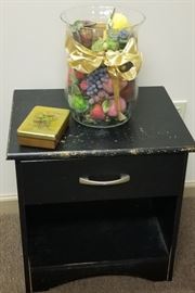 Fake fruit in a glass container and night stand 