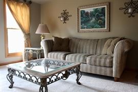Sofa, Stiffel lamp on the left there, glass and metal coffee table and side table, pretty framed art. Sconces, too.