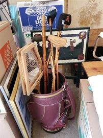 Vintage miniature golf bag and clubs; framed golf print behind golf bag.