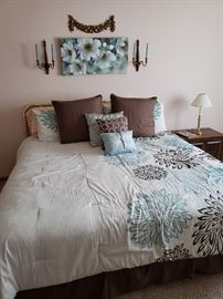 King sized bed with headboard, bedding and matching wall decor.