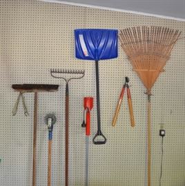 Yard tools including metal and bamboo rake, lawn edger, broom, branch lopper and snow shovel.