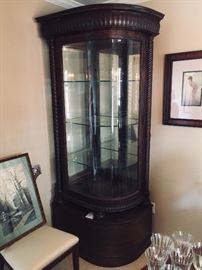 One of a pair of antique corner curved front china cabinets with glass doors and custom built bases. Lighted. 