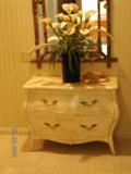 Bombay chest, mirror, and floral  arrangement in hallway.
