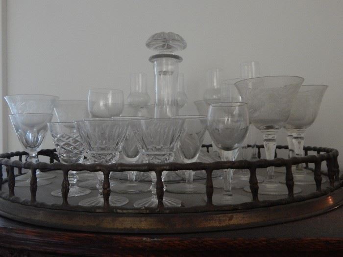 Many and a variety of cordial glasses sitting on a brass tray. 