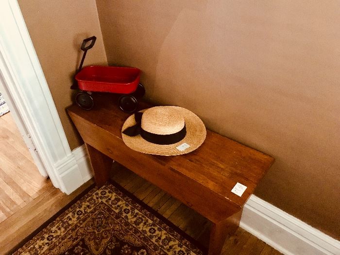 Replica child’s wagon, straw hat, wooden bench, Persian rug