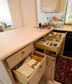 Drawers of silverware, linens, and kitchen gadgets for sale.