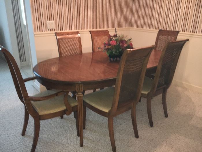 Vintage dining room table and 6 cane-back chairs (2 captain with arms and 4 without arms). Table has 2 leaves and pads.