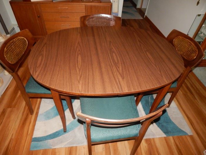 Mid- Century Dining Table and Four Chairs. The surface has a hard finish which has kept it beautiful all of these 50+ years. There are two 18" leaves as well