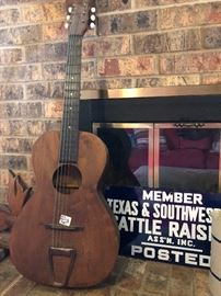 Old guitar and porcelain enamel Texas & Southwestern Cattle Raiser sign.