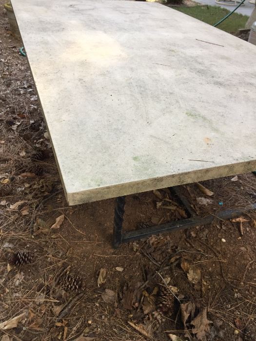 Cement table top on wrought iron base. Measures about: 78" x 42" x 26" high