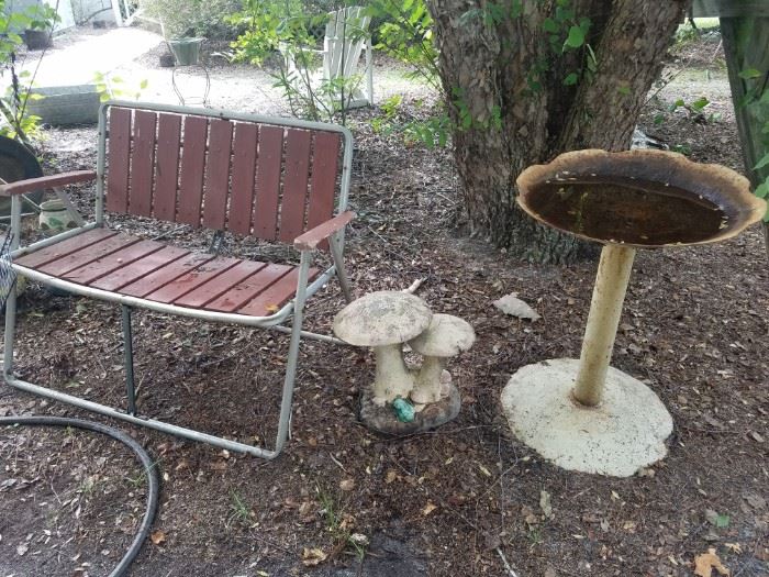 Folding outdoor double chair, concrete mushrooms, metal discs birdbath.