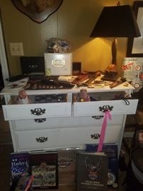 White dresser, art deco turtle lamp, Harley Davidson coffee table books, cigar boxes, cigar cutters, knives, arrowheads, & more.