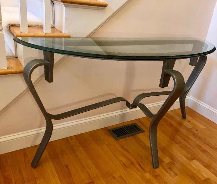 Foyer console table with heavy metal base and thick glass demi-lune top.