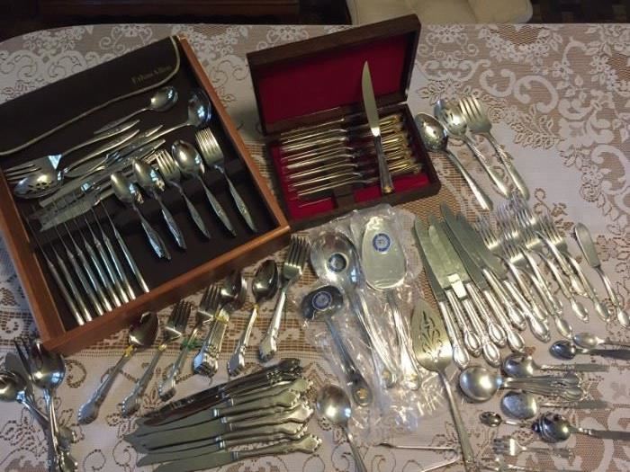 Multiple sets of flatware, both plated silver and stainless steel.  Most in excellent conditions, many unused.