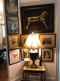 grouping of artwork with pair of gold-decorated tables.  All the artwork in this house is beautifully framed.